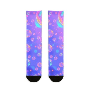 Könnte beinhalten: Ein Paar Socken mit einem lebendigen, farbenfrohen Blasenmuster. Die Socken haben einen lila Hintergrund mit zahlreichen schillernden Blasen in verschiedenen Größen. Das Design enthält Akzente in Pink, Blau und Gelb.