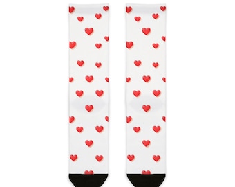 May include: A pair of white socks with a pattern of red hearts. The socks have black heels and toes. The hearts are scattered across the socks.