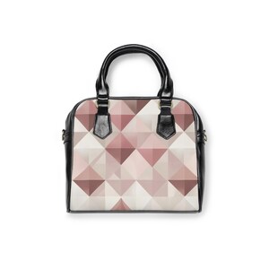 Könnte beinhalten: Schwarze und weiße Handtasche mit einem geometrischen Muster in Rosa- und Beigetönen. Die Tasche hat eine runde Form, einen oberen Griff und einen Schultergurt. Die Tasche ist aus strapazierfähigem Material gefertigt.