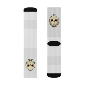 Könnte beinhalten: Hellgraue Socken mit einem Cartoon-Küken-Design. Die Socken haben schwarze Akzente an Zehen und Bündchen. Jede Socke zeigt eine andere Ansicht des Kükens, mit gelbem Körper, braunen Augen und grünen Akzenten.