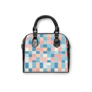 Könnte beinhalten: Eine schwarz-weiße Handtasche mit einem farbenfrohen pixeligen Muster in Blau-, Rosa- und Beigetönen. Die Tasche hat eine runde Form, einen oberen Griff und einen Schultergurt. Die Tasche ist aus Leder.