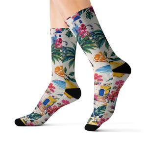 Könnte beinhalten: Crew-Socken mit einem farbenfrohen tropischen Design. Die Socken zeigen Illustrationen von Gebäuden, Palmen, Blumen und Orangenscheiben auf cremefarbenem Hintergrund. Die Fersen und Zehen sind schwarz.