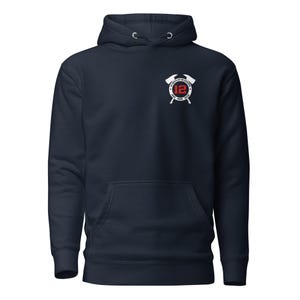 Puede incluir: Sudadera con capucha azul marino con bolsillo delantero y un emblema blanco en el pecho. El emblema presenta un círculo rojo con el número 12, rodeado de texto blanco y hachas cruzadas. La sudadera tiene una capucha con cordón.