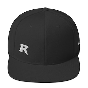 May include: Black flat-brimmed baseball cap with a white embroidered "R" on the front. The cap has a structured fit and a curved brim. The cap is a solid black color.