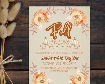 Pode incluir: Um convite para um chá de panela com tema de outono com uma coroa de flores, abóboras e o texto "Fall in Love". O convite inclui o nome da noiva, a data, a hora e o local.