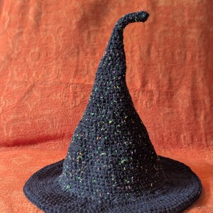 Peut inclure: Chapeau de sorcière en crochet bleu foncé, fait à la main, avec un large bord et un sommet pointu incurvé. Le chapeau est parsemé de mouchetures colorées. Idéal pour Halloween ou les fêtes costumées.