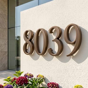 Puede incluir: Un conjunto de números de casa tridimensionales de color bronce que muestran el 8039, montados en una pared de color blanco roto texturizada. Los números presentan una fuente serif clásica y proyectan sombras definidas sobre la superficie, sobre flores.