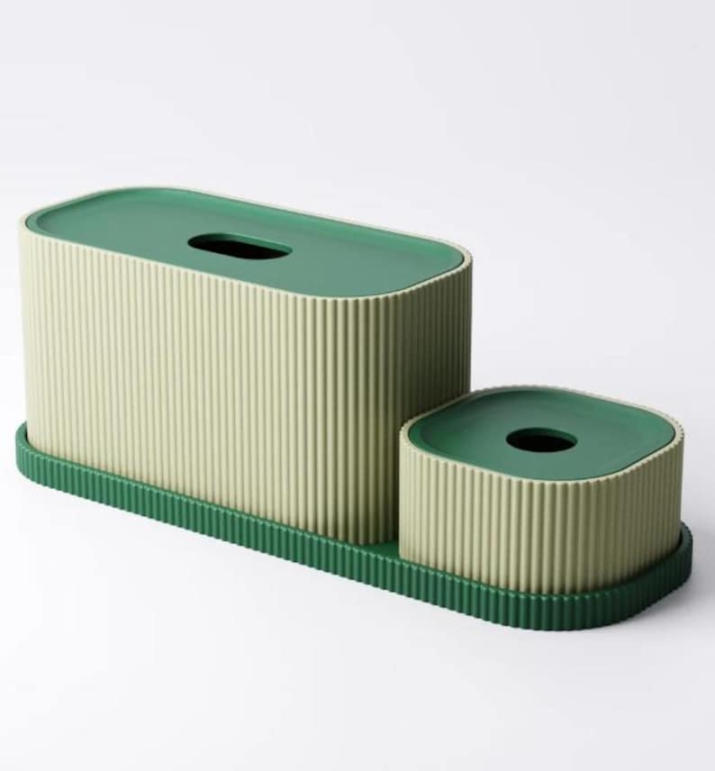May include: A two-piece tissue box and container set. The set features a light green ribbed design with dark green lids and a matching base. The rectangular tissue box has a slot opening, and the smaller container has a circular opening.