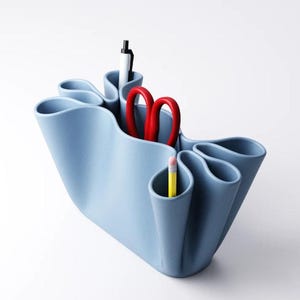 Könnte beinhalten: Ein hellblaues Schreibtisch-Organizer mit mehreren Fächern. Er enthält einen schwarzen Stift, eine rote Schere und einen gelben Bleistift. Das Design ist wellenförmig, mit geschwungenen Kanten und einer modernen Ästhetik. Der Hintergrund ist weiß.