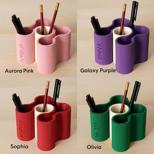 May include: Four colourful desk organisers, each with a unique name: Aurora Pink, Galaxy Purple, Sophia, and Olivia. Each organiser holds pens and pencils. The organisers are in pink, purple, red, and green.