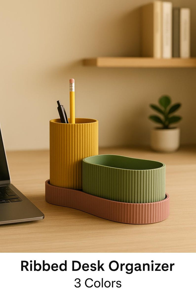 May include: A ribbed desk organizer in mustard yellow, olive green, and dusty rose. The organizer includes a tall, cylindrical cup with a pencil and pen, and an oval-shaped container. The base is a matching dusty rose color.