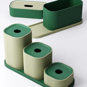 May include: A set of four green and beige ribbed containers. The set includes a rectangular tissue box, a tall open container, and three cylindrical containers with lids. The lids and the base trays are green.