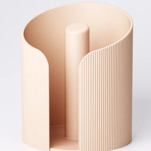May include: A beige paper towel holder with a cylindrical design. The holder has a central post and a curved, ribbed exterior. The open design allows easy access to paper towels. The holder is made of a solid material.
