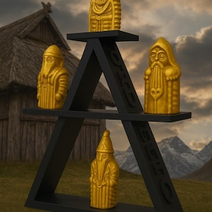 Può includere: Quattro statue dorate di figure barbute su una mensola triangolare nera. Le statue hanno mantelli con cappuccio e sono esposte sullo sfondo di una catena montuosa e di un edificio tradizionale in legno.