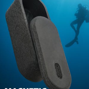 Puede incluir: Una caja fuerte magnética negra para llaves, abierta para revelar el interior. La superficie texturizada de la caja fuerte contrasta con el interior liso y oscuro. Las palabras "MAGNETIC KEY SAFE" se muestran en texto blanco. Un buceador está en el fondo.