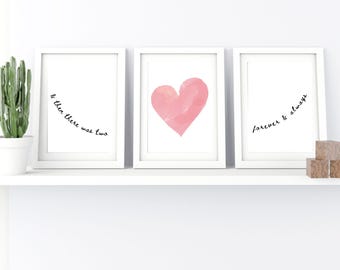 May include: Three framed art prints with white frames. One print has a pink watercolor heart, another reads "& then there was two", and the third says "forever & always". A small cactus in a white pot and wooden blocks are also on the shelf.
