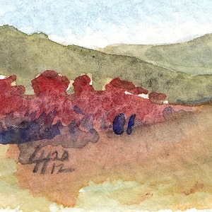 Puede incluir: Pintura acuarela de un paisaje con una colina verde en el fondo y un primer plano rojo y marr&oacute;n con acentos azules. La pintura est&aacute; firmada "Gess 11-12".
