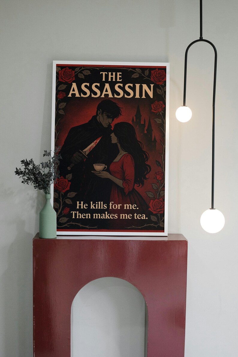 May include: Framed art print featuring a romantic illustration with the text "THE ASSASSIN." The image depicts a man holding a knife and a woman in a red dress holding a teacup, with the text "He kills for me. Then makes me tea."