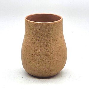 May include: A handmade, speckled ceramic vase with a rounded base and a slightly flared rim. The vase has a warm, earthy tone with a textured surface. The interior is a lighter shade of brown.