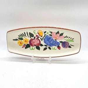 May include: Rectangular ceramic serving platter with a cream-colored base and a brown rim. The platter is decorated with a colorful floral and fruit design, including yellow flowers, purple plums, and blue grapes.