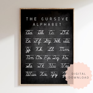 May include: A framed chalkboard-style print featuring the cursive alphabet in white lettering. The title "THE CURSIVE ALPHABET" is at the top. A pink digital download sticker is on the bottom right. The frame is a light brown color.