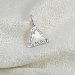 May include: Silver charm in the shape of a mountain with the word "SUMMIT" inscribed on the front.