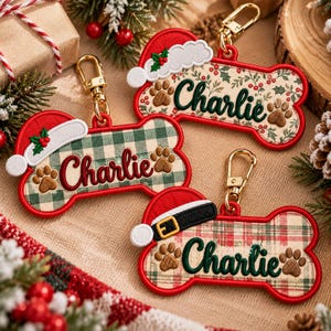 May include: Three bone-shaped keychains with gold-tone lobster clasps. Each features the name Charlie embroidered in dark green or red, accompanied by brown paw prints. Designs include a Santa hat, holly, and various plaid patterns.