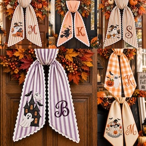 May include: A collection of decorative fabric door ribbons featuring various Halloween motifs including ghosts, pumpkins, witches, and haunted houses, paired with embroidered monograms in striped or checkered patterns with scalloped edges.