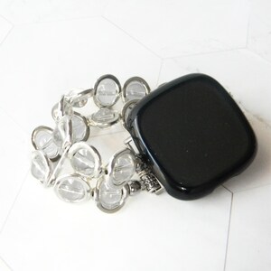 May include: A black square watch face with a clear crystal beaded band.