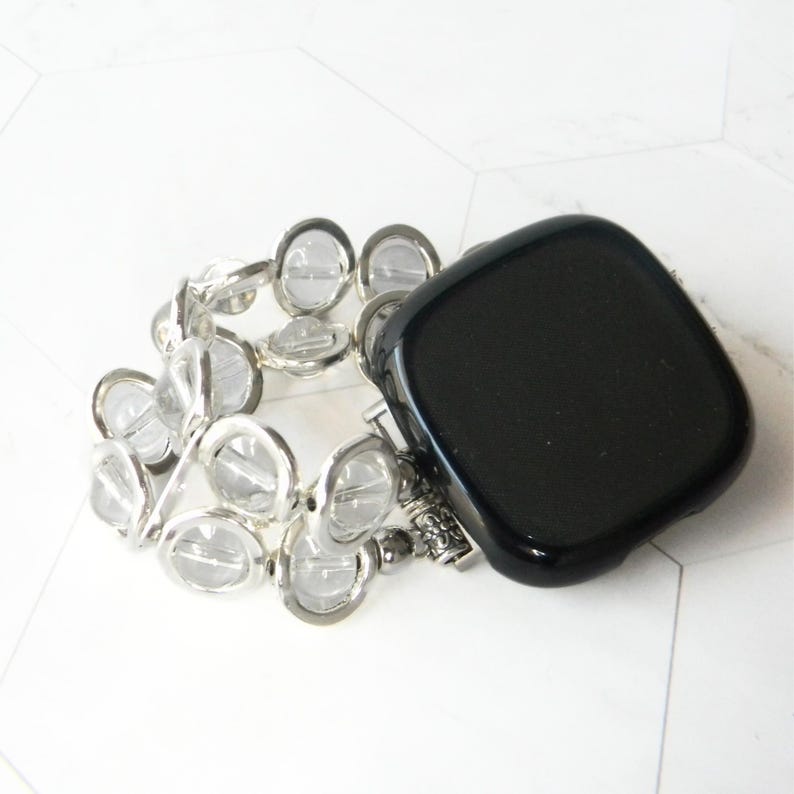 May include: A black square watch face with a clear crystal beaded band.