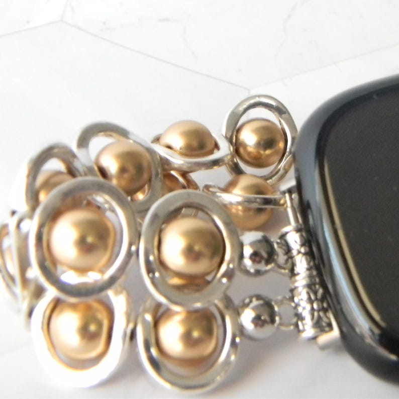 May include: A silver and gold charm bracelet with a black onyx charm. The bracelet features a series of silver rings with gold beads.