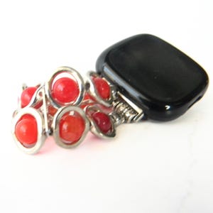 May include: A silver watch band with red gemstone beads. The band is designed to fit a smart watch.