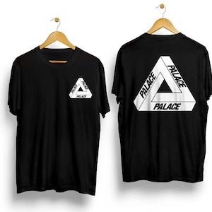 Puede incluir: Dos camisetas negras con la palabra "PALACE" en blanco, formando un dise&ntilde;o triangular. Una camiseta tiene el logo en el pecho, la otra en la espalda. Ambas cuelgan de perchas de madera.
