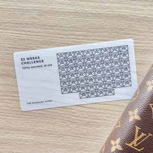 May include: A white savings challenge card with a grid of 52 numbered boxes, each representing a week. The card reads "52 Weeks Challenge" and "Total Savings: $1,378". The Blushing Hippo is printed at the bottom.