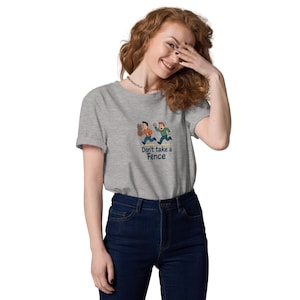 Peut inclure: T-shirt gris clair avec une illustration de dessin animé de deux personnages fuyant une clôture. Le texte "Don't take a Fence" est imprimé en dessous. Le t-shirt est fait d'une matière douce.