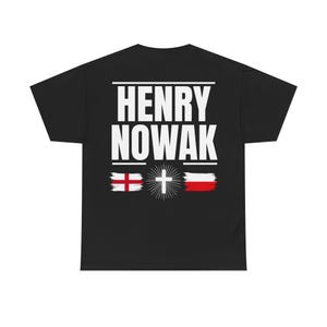 Op de afbeelding: Een zwart t-shirt met korte mouwen en de witte tekst HENRY NOWAK op de achterkant. Onder de tekst staat een afbeelding bestaande uit de vlag van Engeland aan de linkerkant, een wit kruis met stralen in het midden en de vlag van Polen aan de rechterkant.