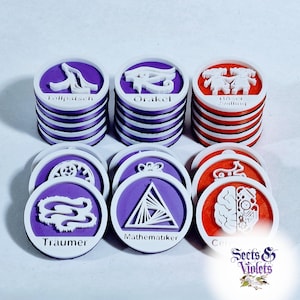 Puede incluir: Una colección de fichas redondas y en capas en morado, blanco y rojo. Cada ficha presenta un gráfico blanco único y texto, incluyendo "Träumer" y "Mathematiker". Las fichas están apiladas en pequeños montones.