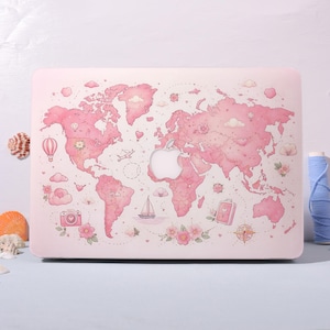 May include: A laptop hard shell case featuring a light pink world map illustration. The design includes small travel-themed icons such as a hot air balloon, a sailboat, a camera, a suitcase, a compass, and various floral accents scattered across the continents.