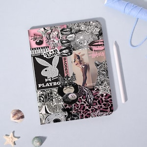 May include: A rectangular notebook featuring a collage of black, white, and pink graphics including a Playboy bunny logo, an 8-ball, leopard print patterns, a disco ball, lips, the text Parental Advisory, Star Girl, and Swag, with rounded corners.