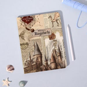Könnte beinhalten: Ein rechteckiger Notizbuchumschlag mit einer Collage im Vintage-Stil und dem Text The Marauders Map, Welcome to Hogwarts sowie London to Hogwarts. Das Design enthält Illustrationen eines Schlosses, eines Drachen und handschriftlicher Notizen.