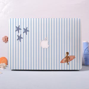 May include: A laptop case with a blue and white striped pattern. The case features three blue starfish stickers and a cartoon monkey surfing on a red surfboard. The Apple logo is visible.