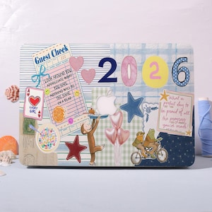 May include: A decorative laptop skin featuring a collage design with the numbers "2026". The design includes a "Guest Check" with text, hearts, stars, a monkey, and frogs on a bicycle. The text "LUCKY GIRL" is also visible.