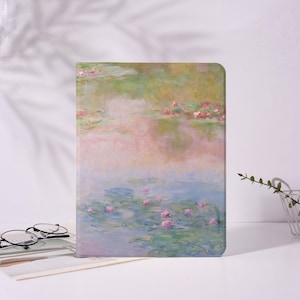 Puede incluir: Una funda rectangular para tableta con una pintura pastel de nenúfares. La obra de arte representa un estanque con tonos rosas y verdes, con nenúfares y flores flotantes. La funda tiene una paleta de colores suaves y apagados.