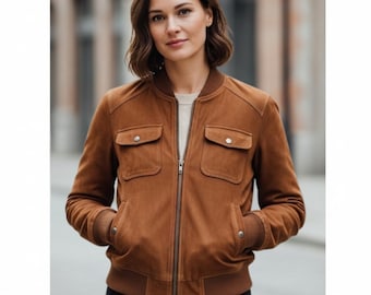 May include: A brown suede bomber jacket with a zip-up front, two chest pockets with button closures, and two side pockets. The jacket has ribbed cuffs and a ribbed hem. The model is wearing a light-colored shirt underneath.
