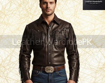 May include: A dark brown leather shirt with fringe detailing on the sleeves and yoke. The shirt has a button-down front and a classic collar. The model is wearing blue jeans and a brown belt with a decorative buckle. The Etsy shop logo is in the top right corner.