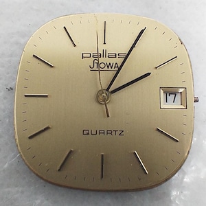 May include: A gold-coloured watch face featuring the brand name "Pallas Siowa" and the word "QUARTZ" at the bottom. The watch face has black hands and markers, with a date window showing the number "17".