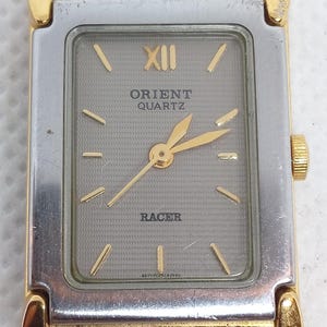 Puede incluir: Una taza de cerámica blanca con un asa negra y el texto "But First, Coffee" en negro y negrita. La taza está sobre una superficie de madera. La taza mide aproximadamente 10 cm de alto.