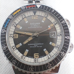 Puede incluir: Un reloj de pulsera Sicura vintage con una correa de acero inoxidable. La esfera es de color gris oscuro con detalles en blanco y dorado, con el texto "SICURA 25 JEWELS SHOCKPROTECTED SUPERWATERPROOF 400 VACUUM TESTED". El bisel tiene marcas en blanco y negro.
