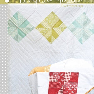 May include: A white quilt with a red, white, and yellow patchwork design. The quilt features a diamond pattern with three colorful starbursts. The text "Angela Yosten PATTERNS" and "Baby Argyle QUILT" are visible.