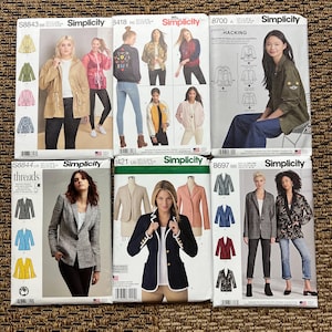 May include: Six Simplicity sewing pattern envelopes featuring various jacket and blazer designs. The patterns include S8843, 3418, 8700, S8844, 1421, and 8697, each displaying illustrations or photographs of finished garments in different colors and styles.